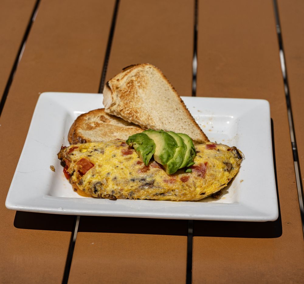 Folded omelet topped with sliced avocado and served with toast